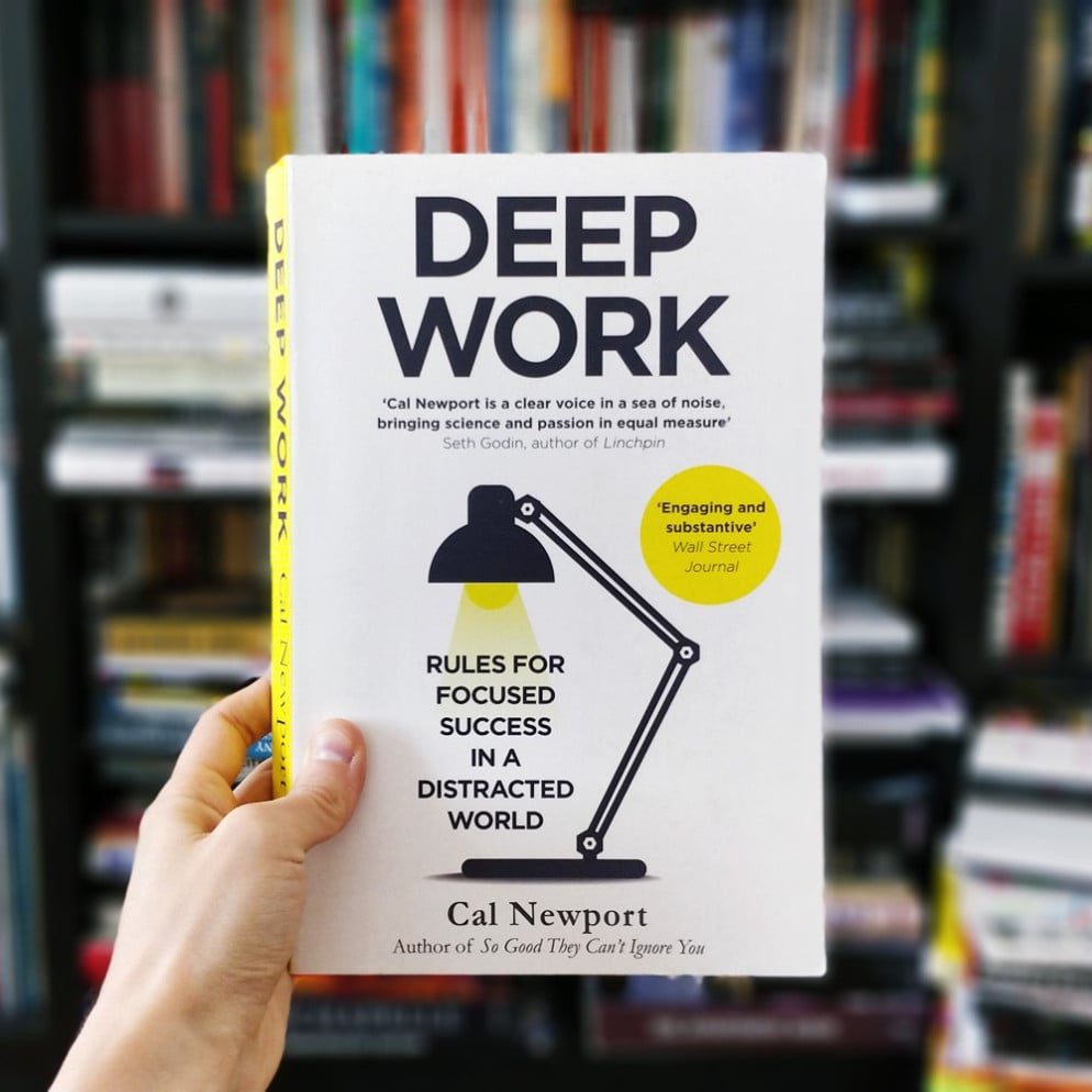 La mano sostiene el libro "Deep Work" de Cal Newport