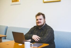 Homem barbudo com camisa de flanela senta-se com um laptop