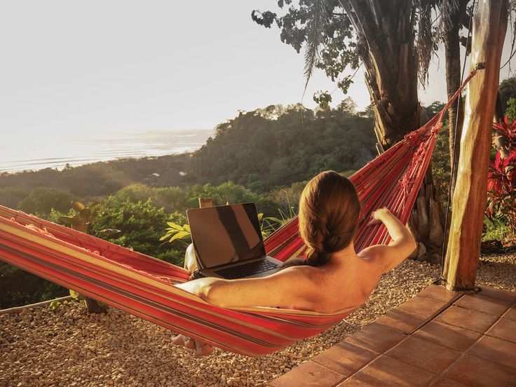 Young woman works fro hammock with tropical forest view