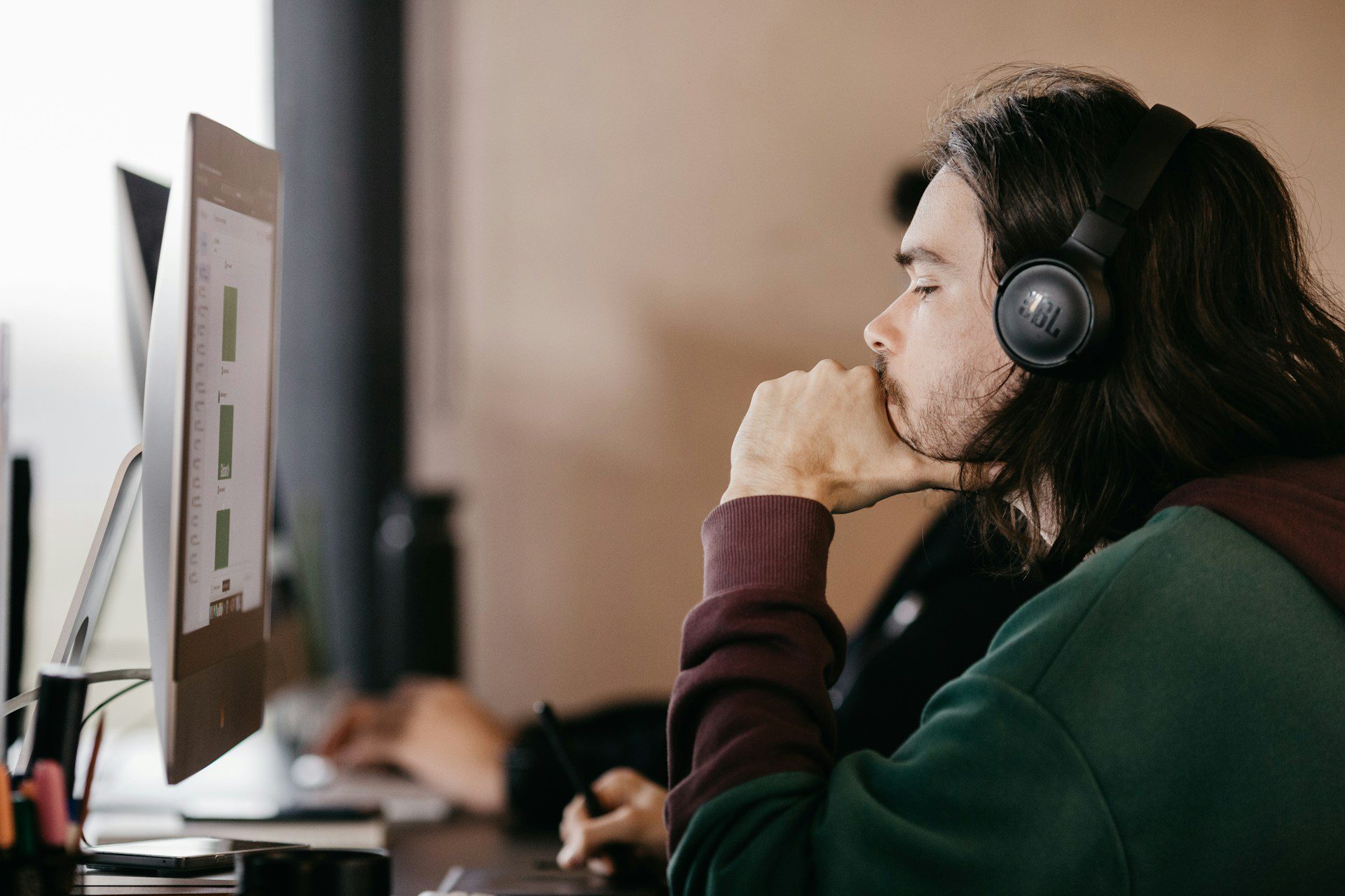 uomo con le cuffie che guarda uno schermo come farebbe una persona con un assistente di intelligenza artificiale che prende appunti durante una riunione